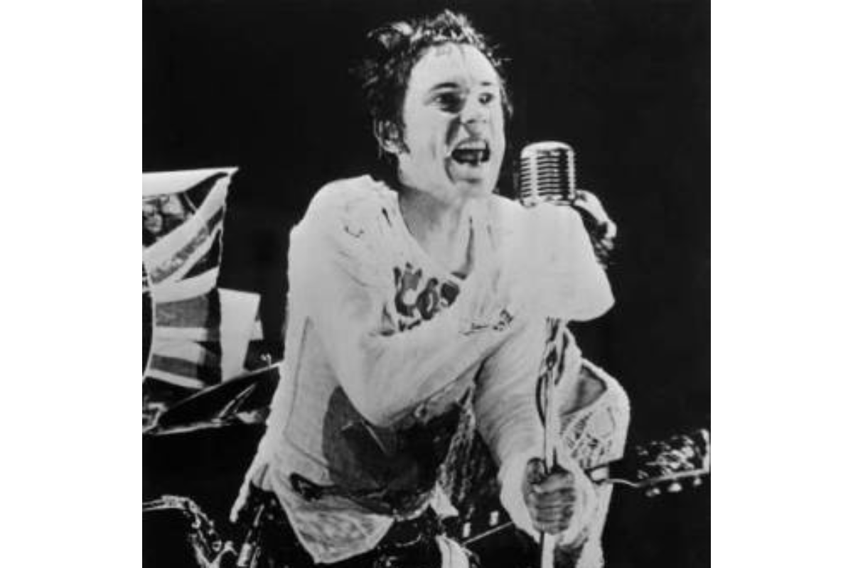 Johnny Rotten of the Sex Pistols shouting into a microphone during a live performance (black and white)